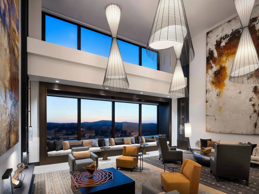 A spacious living area with a large window, modern furniture, and abstract art.