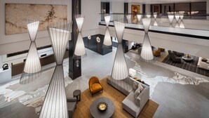 A modern lobby with unique wireframe pendant lights, a central seating area with sofas and a coffee table, and a marble-patterned floor. - Red Hawk Resort & Casino (Placerville)