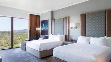 A hotel room with two beds, a large window with a city view, a painting on the wall, and a patterned headboard.