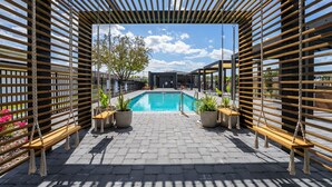 A pool area with wooden slatted walls, potted plants, and a clear blue sky. - 3280 - Beautiful 3br Home near Disney - The Hub at Westside (Kissimmee)