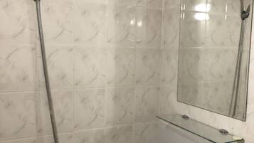 Un baño con ducha, lavamanos y espejo.
