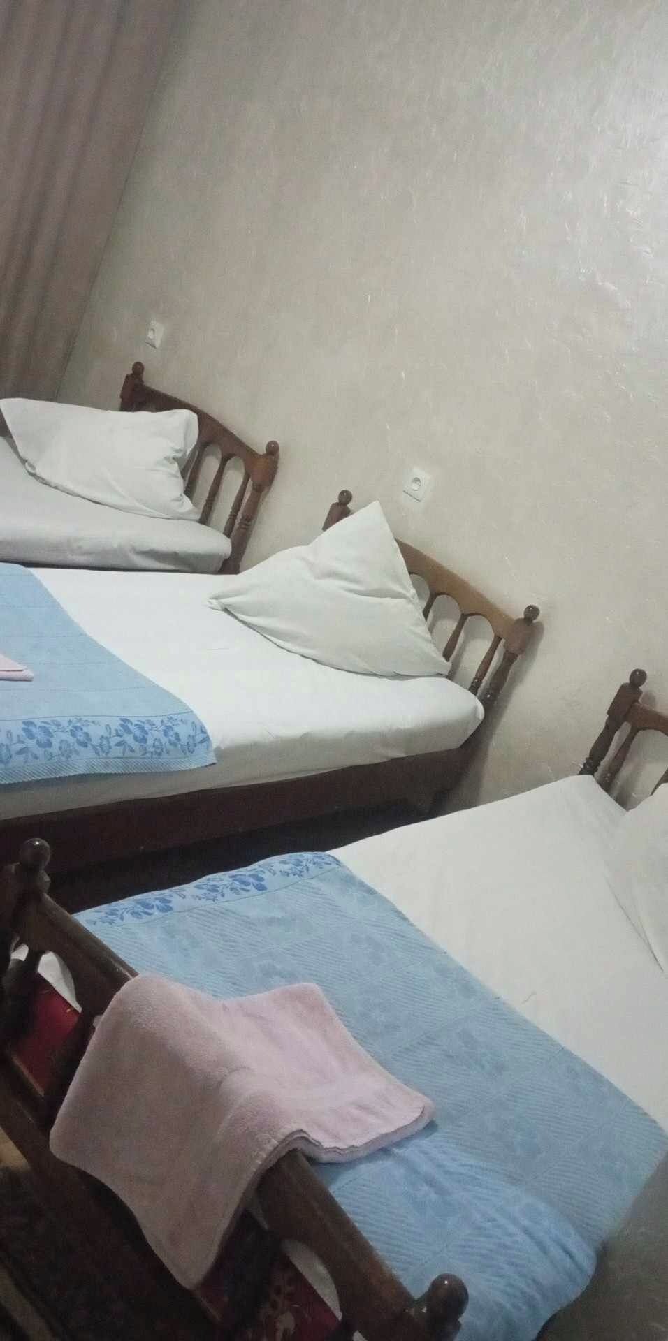 A room with two wooden beds, each with a blue and white bedspread and white pillows.