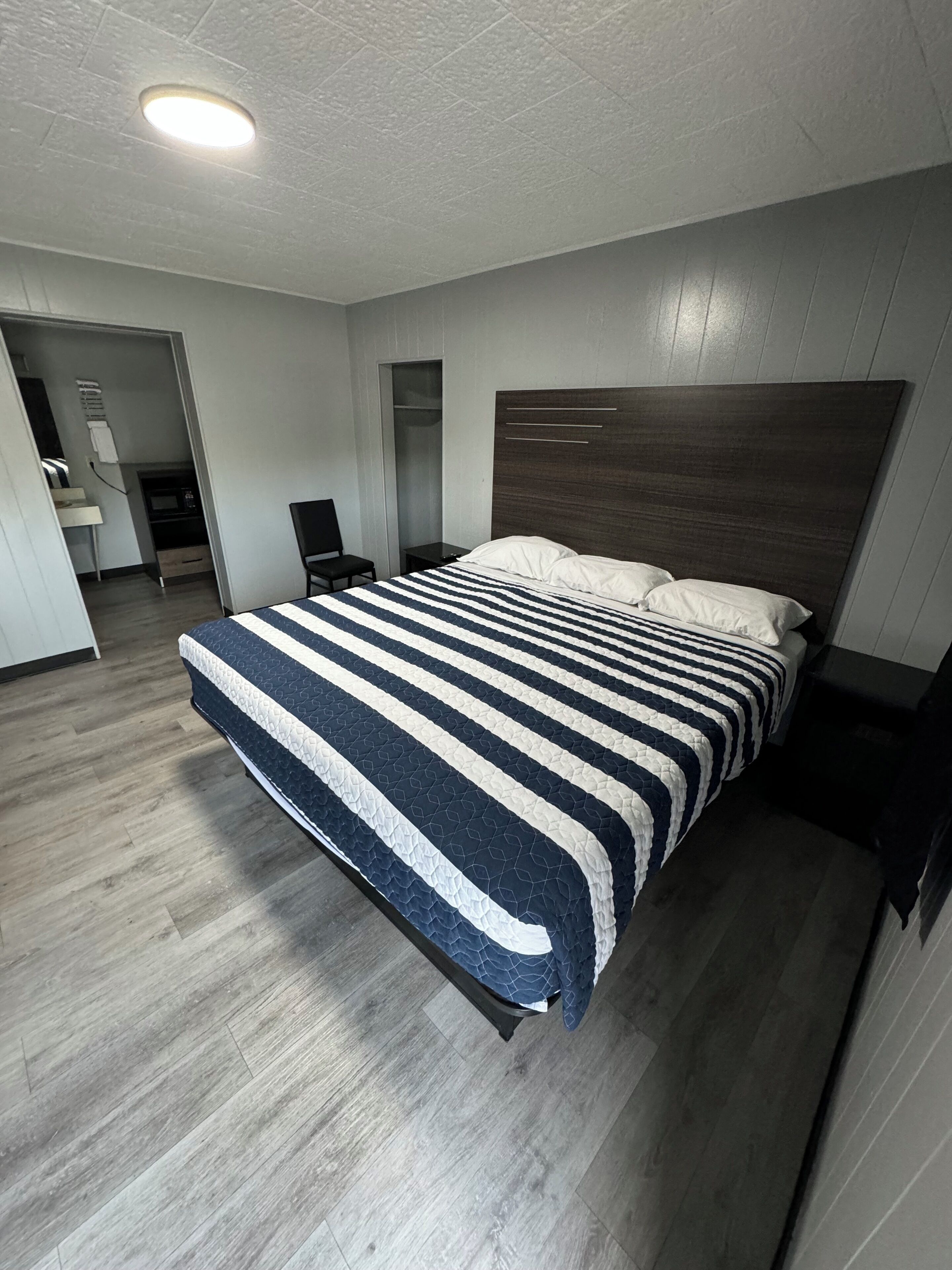 A modern hotel room with a large bed, a wooden headboard, and a built-in wardrobe.