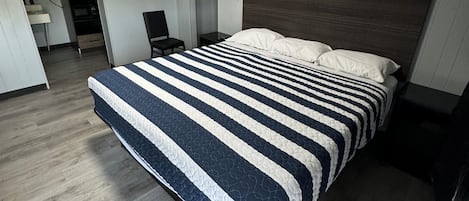 A modern hotel room with a large bed, a wooden headboard, and a built-in wardrobe.