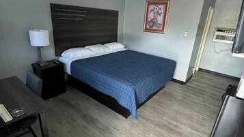Une chambre d’hôtel avec un lit, un bureau, une chaise, une télévision et un tableau encadré au mur.