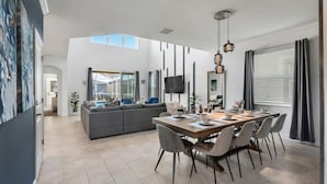 Een moderne eetruimte met een grote tafel, stoelen en hanglampen.