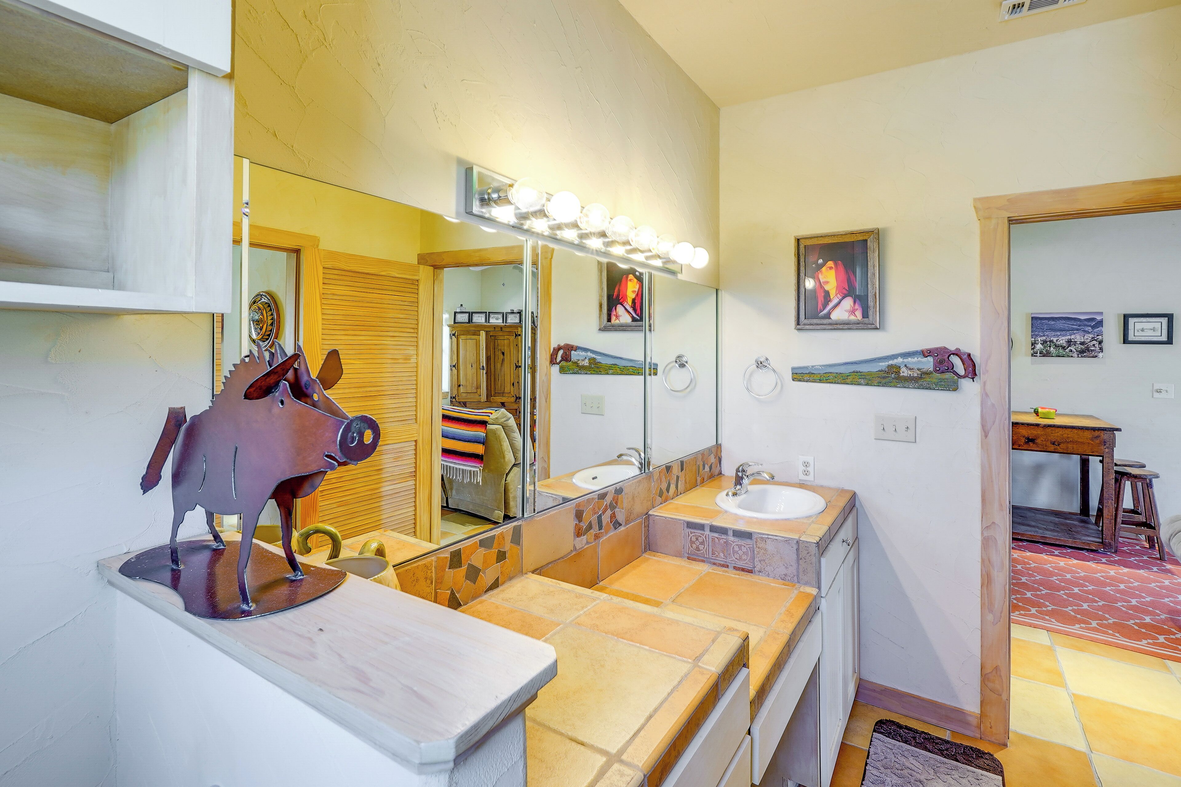Une salle de bain dotée d’un grand miroir, de deux lavabos et d’une sculpture équestre décorative.