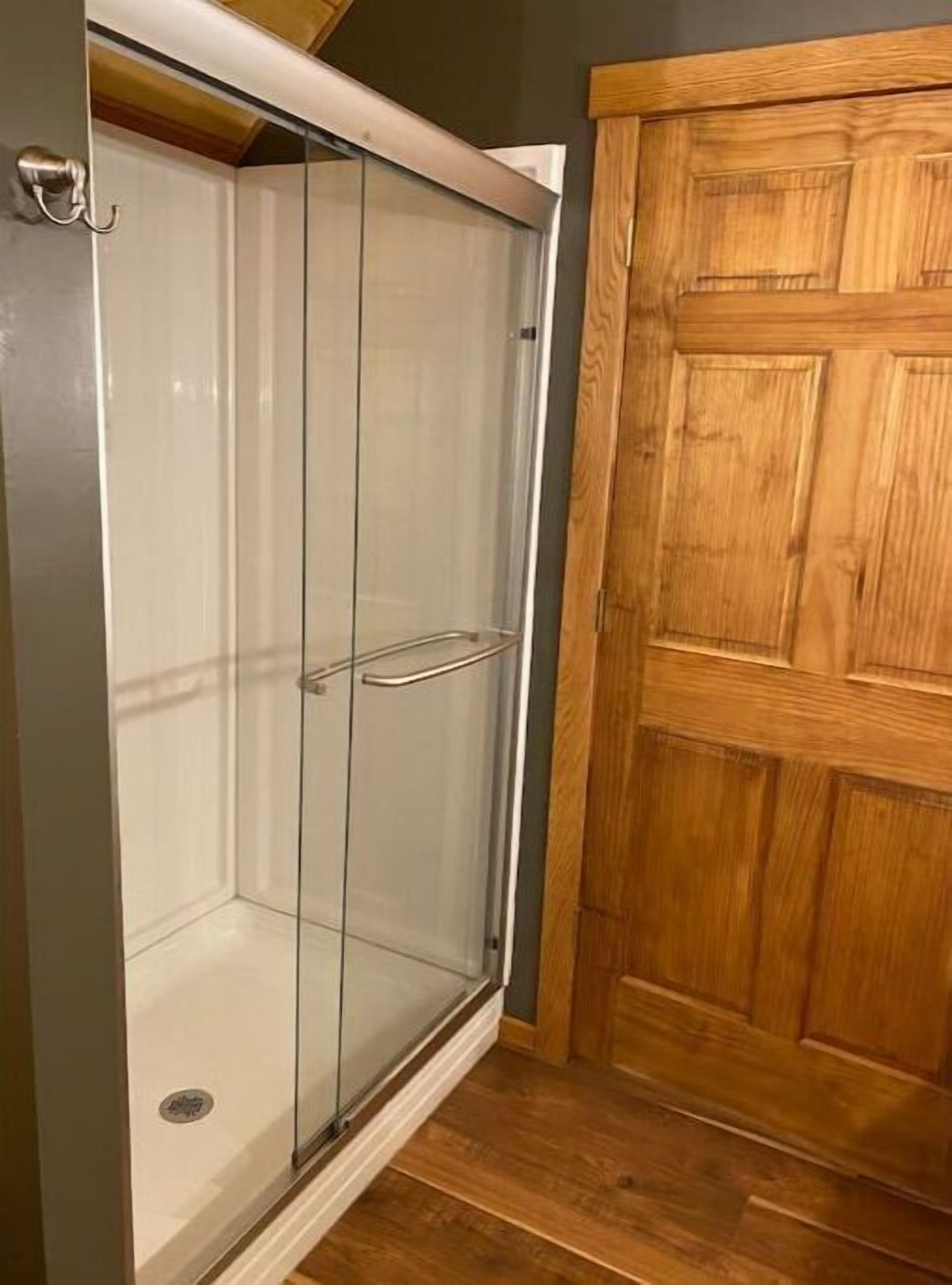 Un vestidor con puerta de madera y cabina de ducha de vidrio.