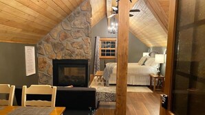 Una habitación acogedora con chimenea de piedra, techo de madera y una cama con mesita de noche.