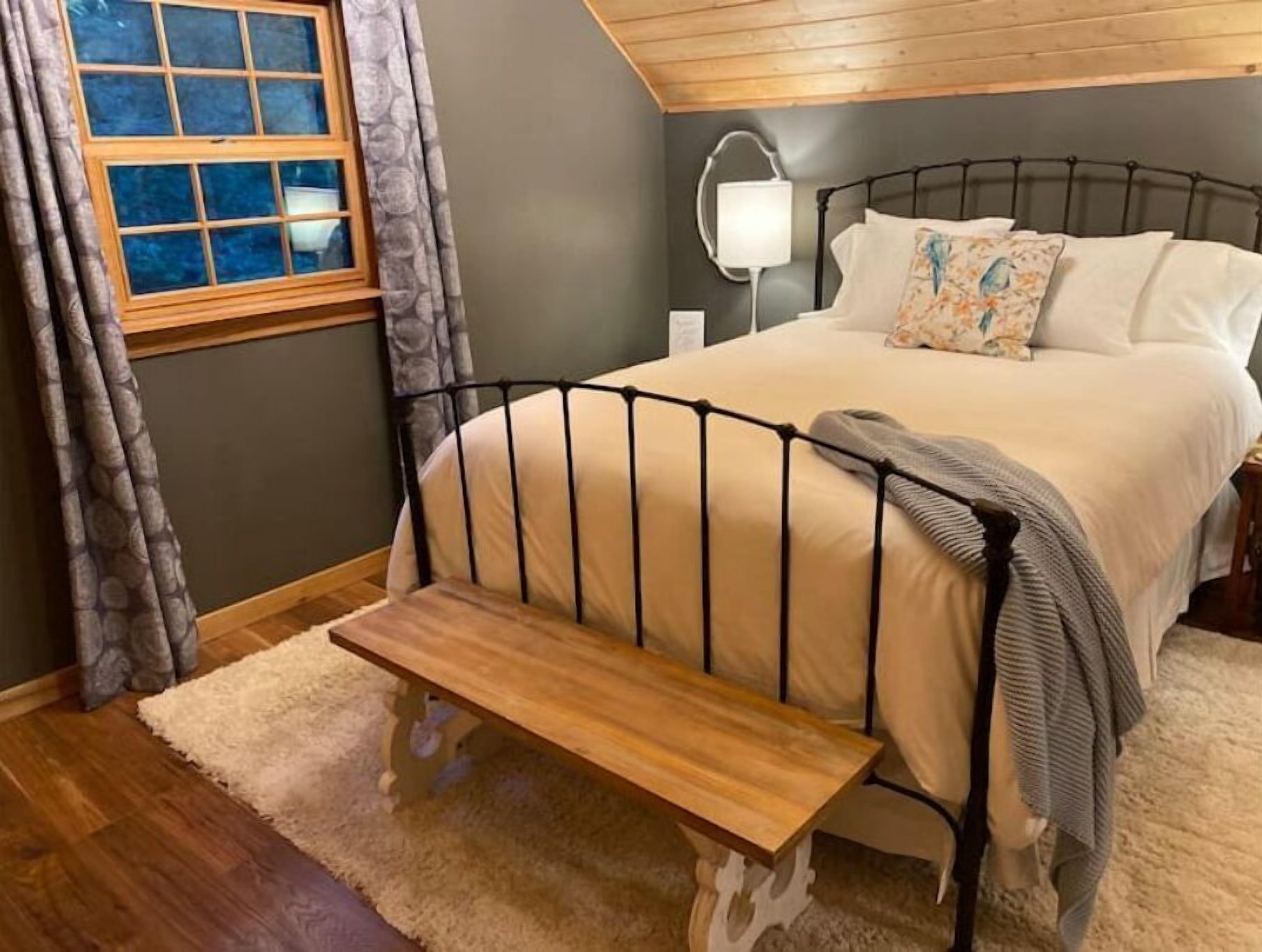 Une chambre à coucher avec un lit, une lampe de chevet et un banc.