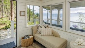 Ein gemütliches Zimmer mit einem beigen Sofa, einem kleinen Tisch und Blick aufs Meer.