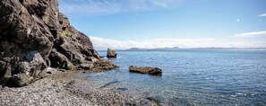Una costa rocosa con agua cristalina y montañas a lo lejos.