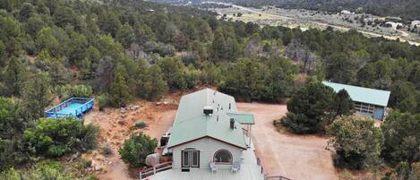Una casa con terraza, rodeada de árboles y montañas.