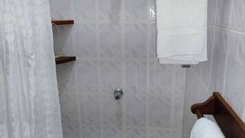 A shower area with a tiled wall, a showerhead, a towel rack, and a shower curtain.
