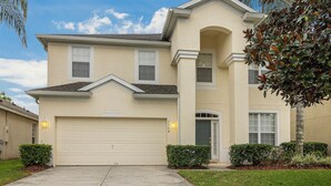 A two-story house with a garage, a front door, and a small porch. - Villa Holidays 7704 WH (Kissimmee)
