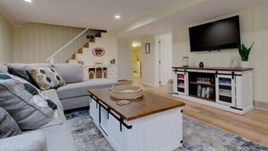 A living room with a sofa, coffee table, TV, and a staircase. - The Manhattan Charm! (Manhattan)