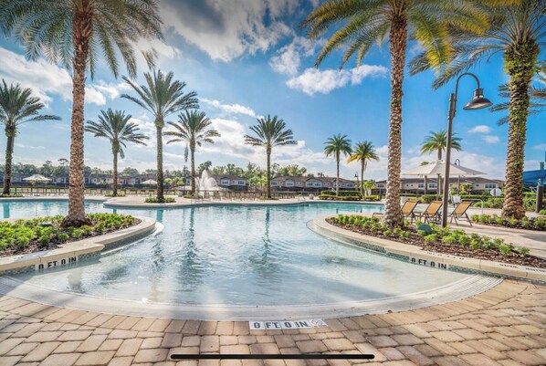 Relax by the resort pool surrounded by palm trees and lounge chairs.