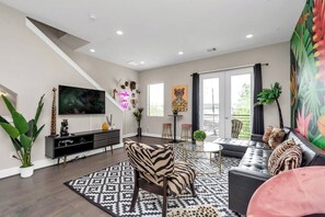 Relax in this stylish living room with a large flat-screen TV, comfortable sofa, and dining area.