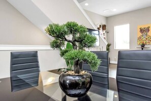 Meetings take place around a glass-top table in this stylish conference room, surrounded by black leather chairs and a unique bonsai tree.