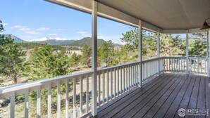 A covered porch with a view of a mountainous landscape.
