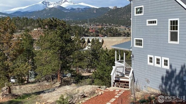 A two-story house with a porch, a mountain view, and a clear sky.
