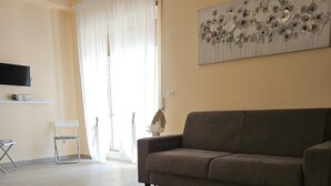 A living room with a sofa, a chair, a flat-screen TV, and a decorative wall piece. - ROYAL HOUSE PALACE (Caserta)
