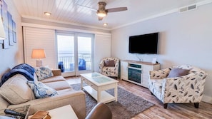 Relax in a spacious living area with a comfortable sofa set, flat-screen TV, and sliding glass door leading to a balcony.