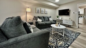 Ein modernes Wohnzimmer mit einem grauen Sofa, einem weißen Couchtisch und einem Teppich mit Muster.