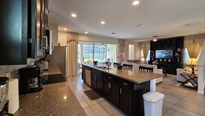 A modern kitchen with dark cabinetry, a granite countertop, and a central island. - Solara Resort private POOL HOME 4 Bed (Kissimmee)