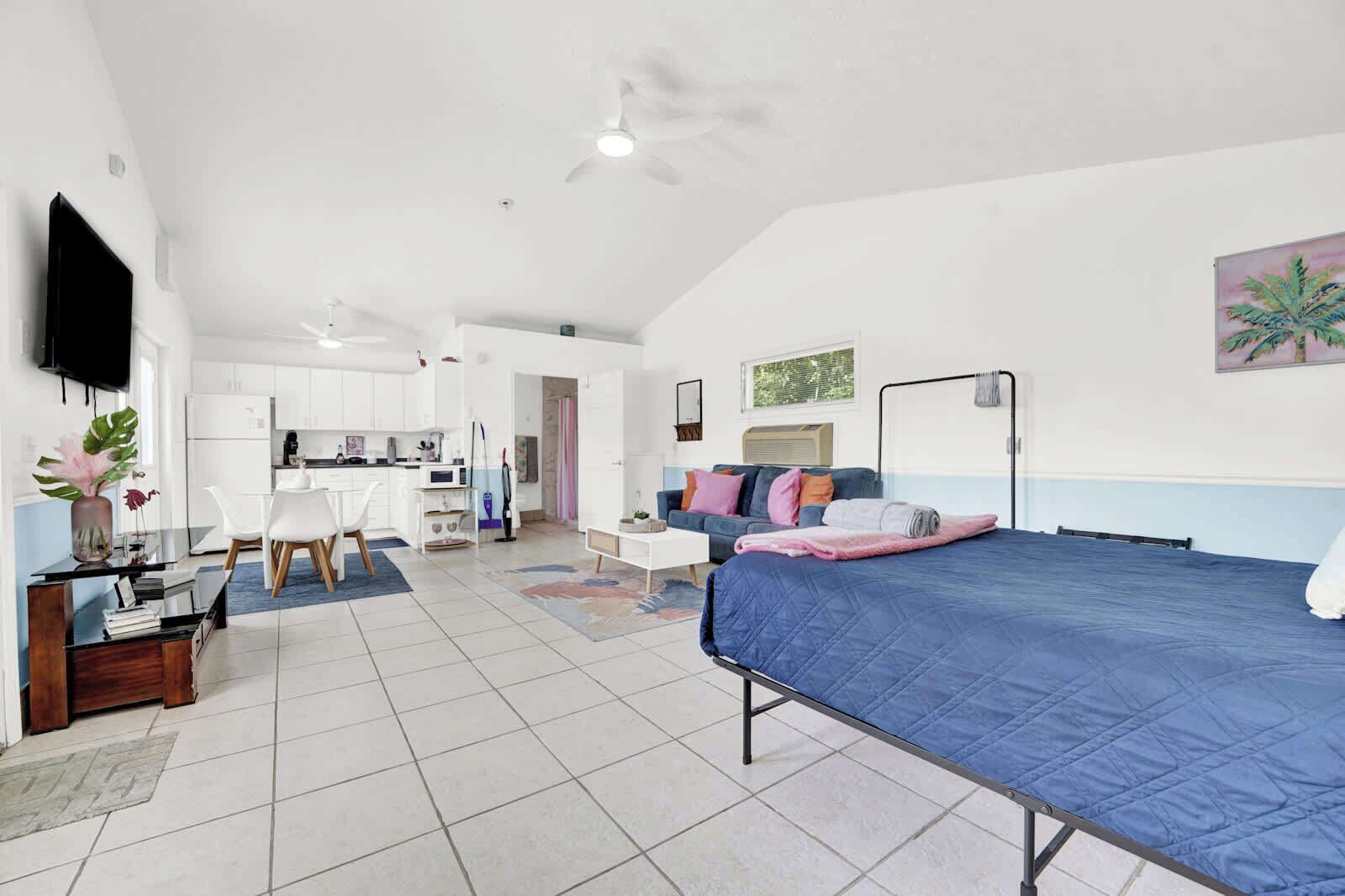 Une chambre compacte et moderne, équipée d’un lit, d’un bureau et d’une kitchenette.