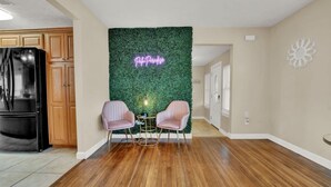 A modern kitchen with wooden cabinets, a black refrigerator, and a green wall with a neon sign. - Spacious Family Retreat with Game Room 25 Mins to PCB (Lynn Haven)