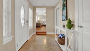 A hallway with white doors, a wooden floor, and a console table with decorative items.