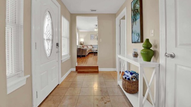 A hallway with white doors, a wooden floor, and a console table with decorative items. - Spacious Family Retreat with Game Room 25 Mins to PCB (Lynn Haven)