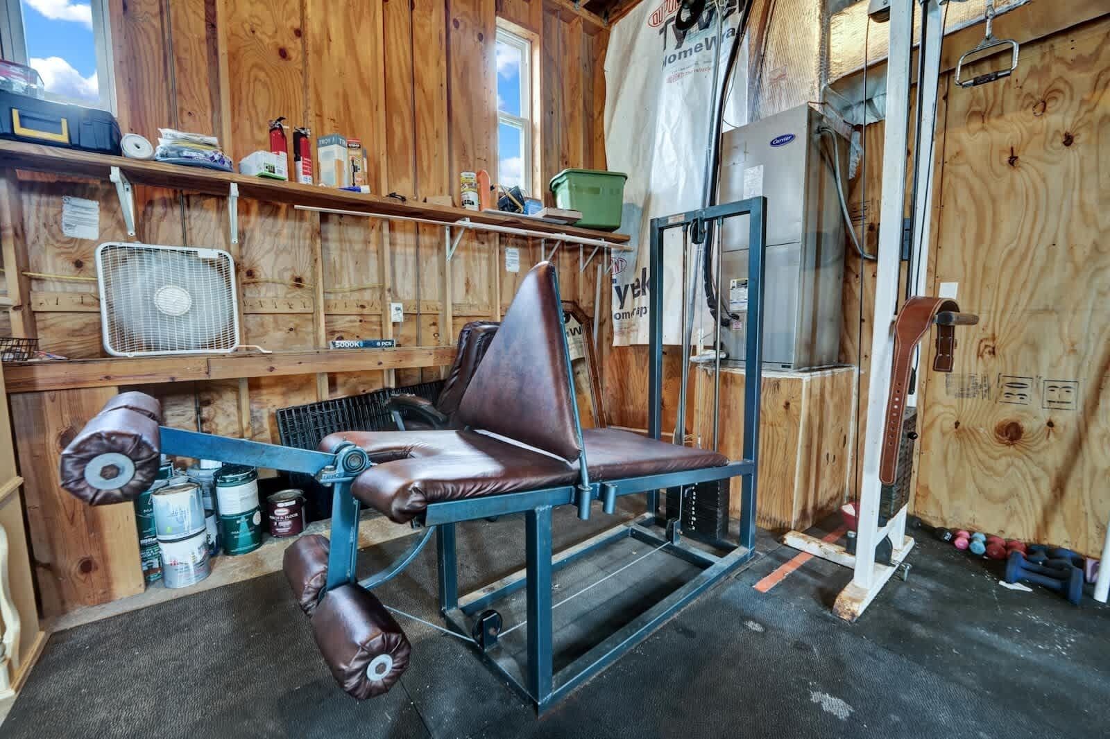 Un atelier équipé d’un fauteuil en cuir, d’un établi en métal et de divers outils et matériaux.