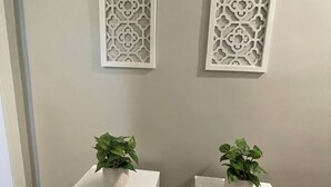 Two white square tables with potted plants, positioned against a wall with decorative white panels. - Nestled within the pines (Chattanooga)