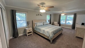 A bedroom with a bed, nightstands, a ceiling fan, and a window with curtains. - Nestled within the pines (Chattanooga)