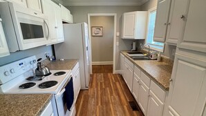 A kitchen with white cabinets, a stove, a microwave, and a refrigerator. - Nestled within the pines (Chattanooga)