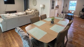A spacious living area with a dining table, sofas, and a TV mounted on the wall. - Nestled within the pines (Chattanooga)