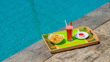 Ein Tablett mit einer Schüssel Pommes, einem Glas rotem Getränk und einer kleinen Ketchup-Pfanne am Pool.