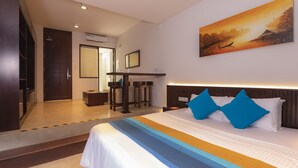 Une chambre d’hôtel avec un grand lit, un tableau au mur et un bureau avec des chaises.