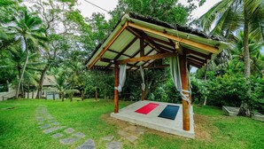 Un kiosque doté d’un toit de chaume, entouré d’une végétation luxuriante et de palmiers.