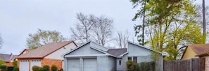 A residential house with a garage, a fenced yard, and a small shed.