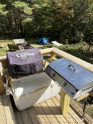 En træterrasse med grill og køleboks.