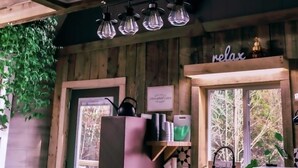 Interno di un rustico chalet con soffitto in legno, angolo cottura con finestra e un cartello con scritto 'relax' sopra il lavello.