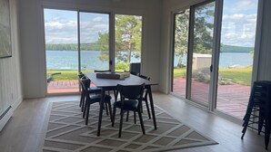 Un comedor con mesa y sillas, ventanas amplias con vista al lago y un ventilador de techo.