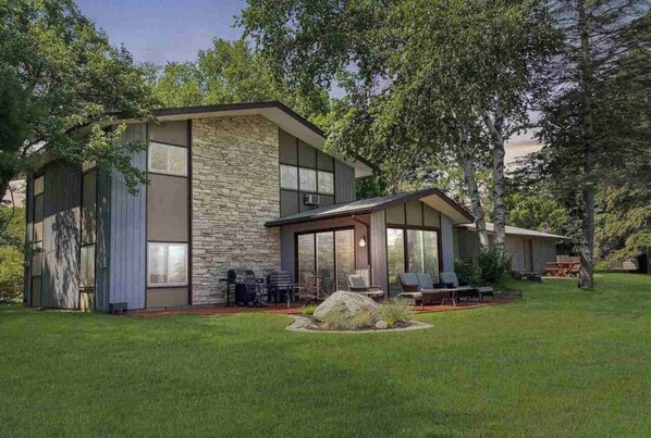A modern two-story house with a stone facade, large windows, and a well-maintained lawn. - Lake Home,1st Floor only, in a quiet Lake Antoine neighborhood. (Iron Mountain)