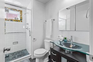 Bathroom features a glass shower enclosure, toilet, and sink with a marble countertop.