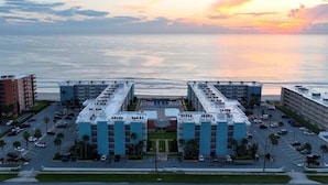A hotel with a central courtyard, multiple floors, and a view of the ocean.