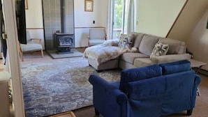 Ein Wohnzimmer mit einer Couch, einem blauen Sessel, einem Kamin und einem großen Fenster.