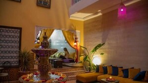 A cozy lounge area with a central fountain, comfortable seating, and a decorative wall. - 66 Av. Imam El Ghazali (Marrakech)